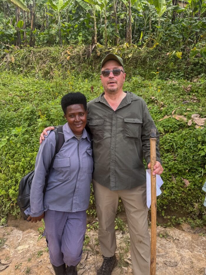 Man and woman pose in Uganda landscape with banana trees.