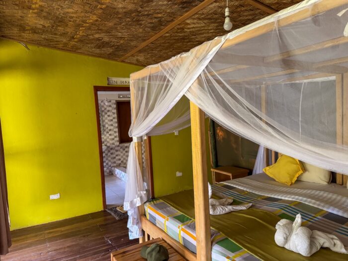 Bedroom with four-poster bed and mosquito net in Uganda.