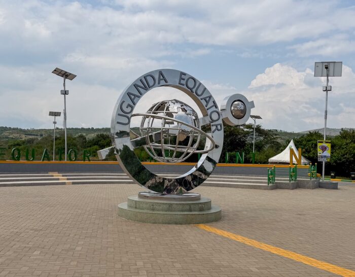 Uganda Equator monument with globe sculpture and text "Uganda Equator Line" on a paved platform.