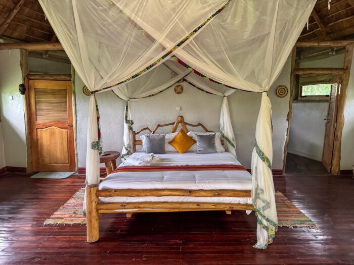 Ugandan bedroom with four-poster bed and mosquito net. Rustic, cozy interior design.