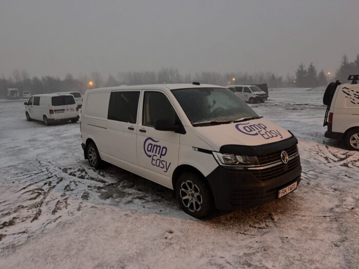 White Camp Easy camper van in Iceland, parked in a snowy lot. "Camp Easy" logo visible on the side.