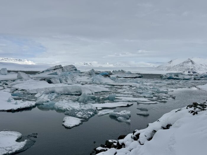 Icebergs in glacial lagoon, Iceland. Snow-covered landscape under a cloudy sky.