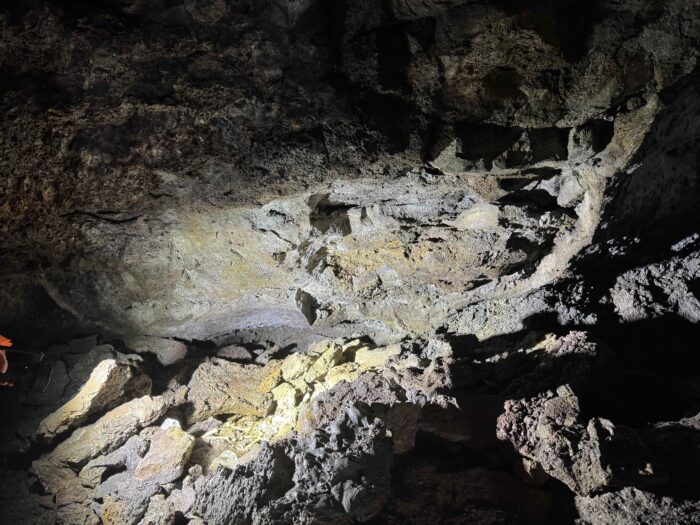 Inside a dark lava cave in Iceland, textured rock formations.