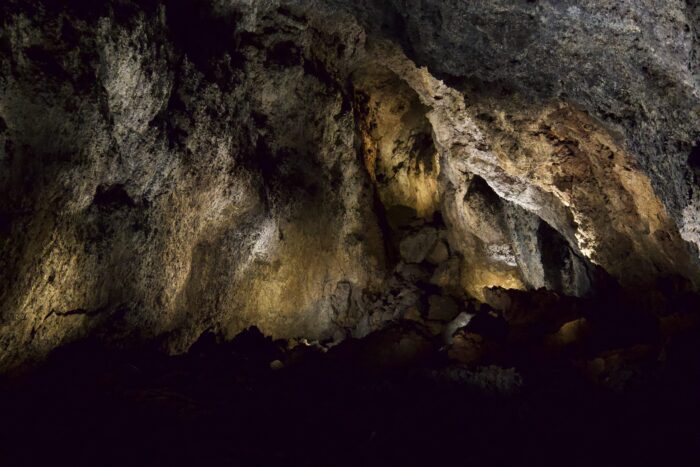 Volcanic cave interior with textured rock formations illuminated by soft lighting.