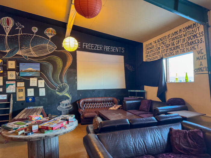 Whale mural, sofas, and game table in a community space with text about openness.