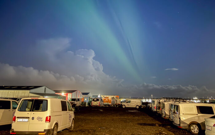 Northern Lights over a parking lot with vans in Iceland