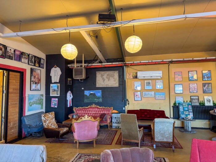 Cozy lounge area with vintage furniture, posters, and a projector screen.